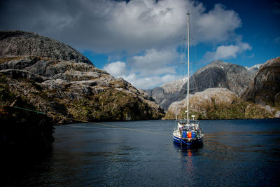 Boat moored on sea against rocky mountains