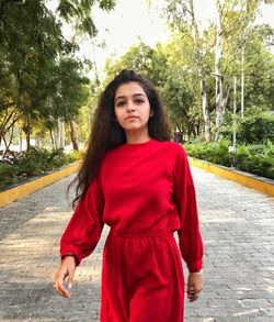 Portrait of beautiful young woman standing against trees