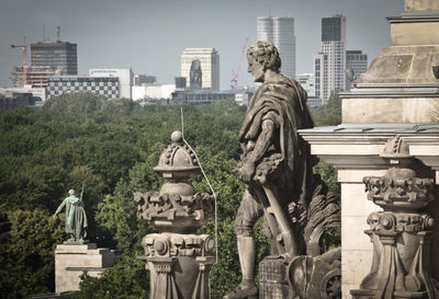 Statue in city against buildings