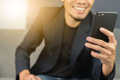 Midsection of man using mobile phone