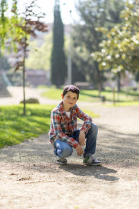 Portrait of teenager boy crouching at park
