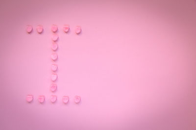 Close-up of heart shape candies over pink background