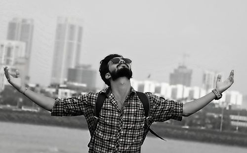 Man with arms outstretched standing in city