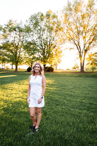 Full length of smiling woman standing on grass at park