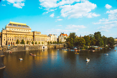 Buildings by river against sky