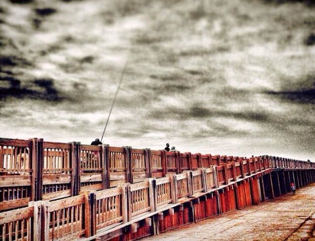 architecture, built structure, building exterior, sky, cloud - sky, railing, cloudy, street light, connection, city, transportation, cloud, overcast, bridge - man made structure, low angle view, outdoors, building, day, bridge, the way forward