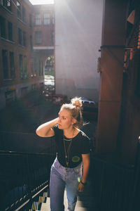 Young woman standing on railing in city