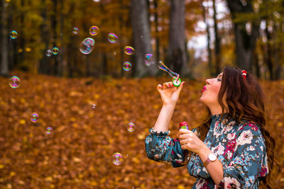 Woman playing with bubble wand in forest