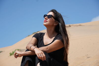 Young woman wearing sunglasses against clear sky