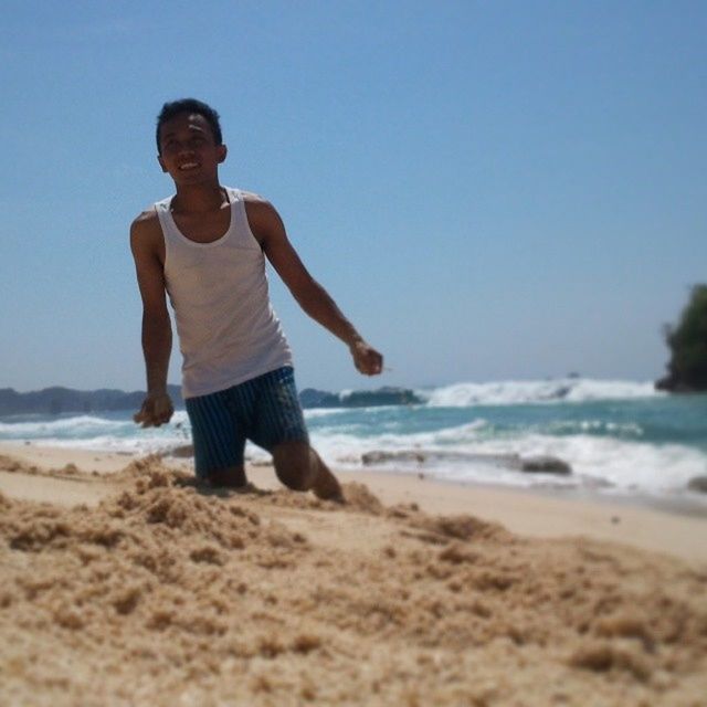 beach, sand, shore, sea, lifestyles, leisure activity, full length, person, casual clothing, water, young adult, vacations, horizon over water, standing, sky, clear sky, young men, front view