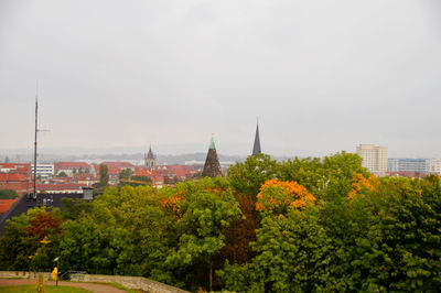 Trees and cityscape against sky