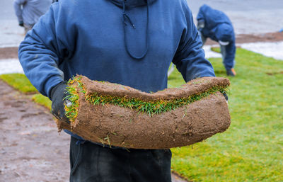 Midsection of man holding turf outdoors
