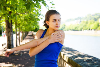 Young woman looking away while standing against trees