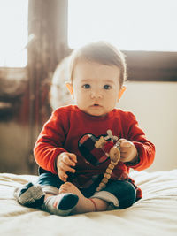 Portrait of cute baby sitting on bed at home