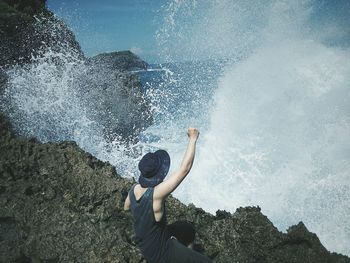 High angle view of man cheering on rock by sea