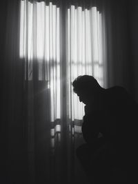Close-up of silhouette person sitting at home