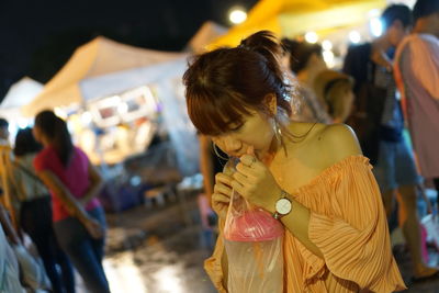 Woman looking at camera while standing on street at night
