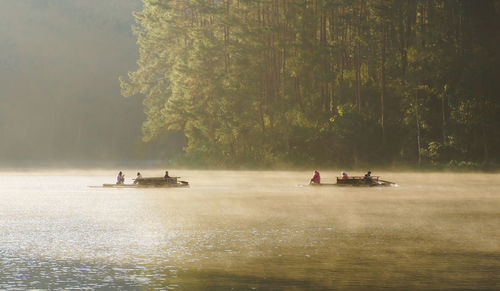 Peoples paddle in a lake in the valley of thailand in the mist and the morning sun.
