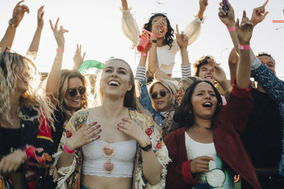 Happy men and women enjoying music at concert in summer