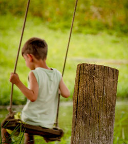 Rear view of boy standing on wood