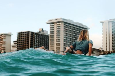 Man sitting in swimming pool against buildings in city