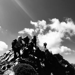 Low angle view of people on rock against sky