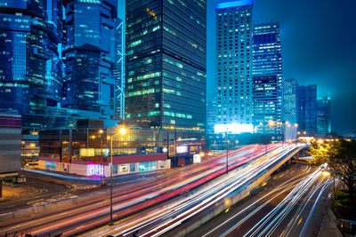 Light trails on city street by buildings at night