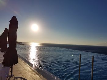 Scenic view of infinity pool by sea against sky during sunset