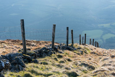 Wire fence descending mountain on hazy day
