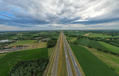 Panoramic view of wind farm or wind park,  with the motorway with few cars and railroad next to it.