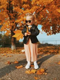 Full length of child standing on tree during autumn