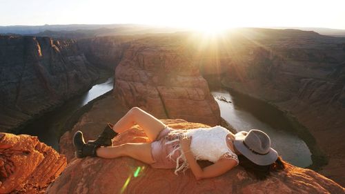 High angle view of woman lying on rock formation against horseshoe bend