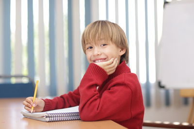 Portrait of smiling boy studying on table at home