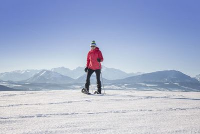 Woman snowboarding on land against clear blue sky