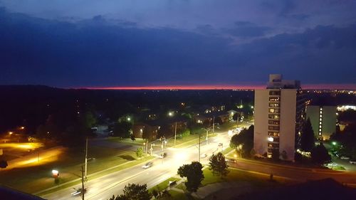 Light trails on road in city against sky at night