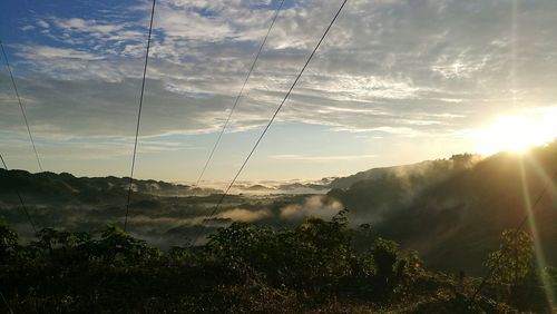 Sun shining through clouds over landscape