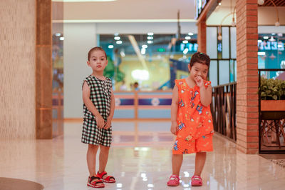 Portrait of siblings standing on tiled floor