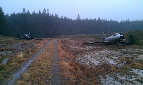 Abandoned fighter planes on field against sky