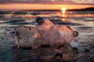 Close-up of plastic bottles thrown on the shore in the backlight