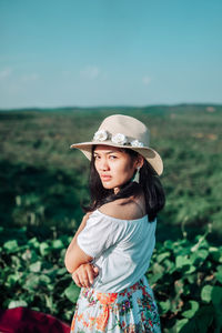 Portrait of young woman standing against sky