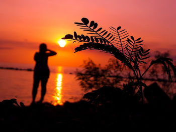 Silhouette person standing on beach against sky during sunset