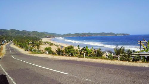 Road by sea against clear sky