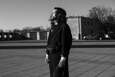 Man looking away in city against sky