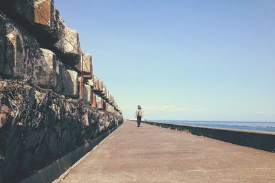 Man standing at beach against clear sky