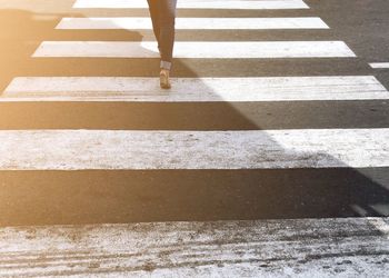 Low section of woman walking on zebra crossing