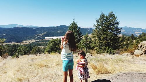 Siblings standing on ground against sky