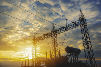 Low angle view of silhouette cranes against sky during sunset
