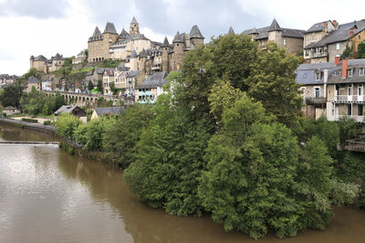 River amidst buildings and trees against sky