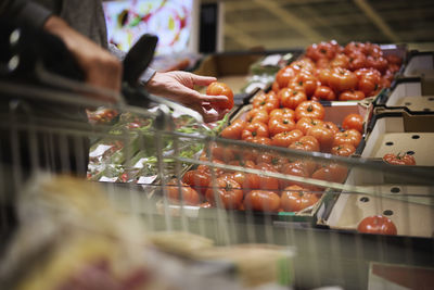 Customer's hand holding beefsteak tomato in store