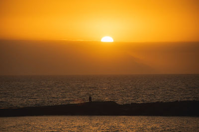 Scenic view of sea against orange sky